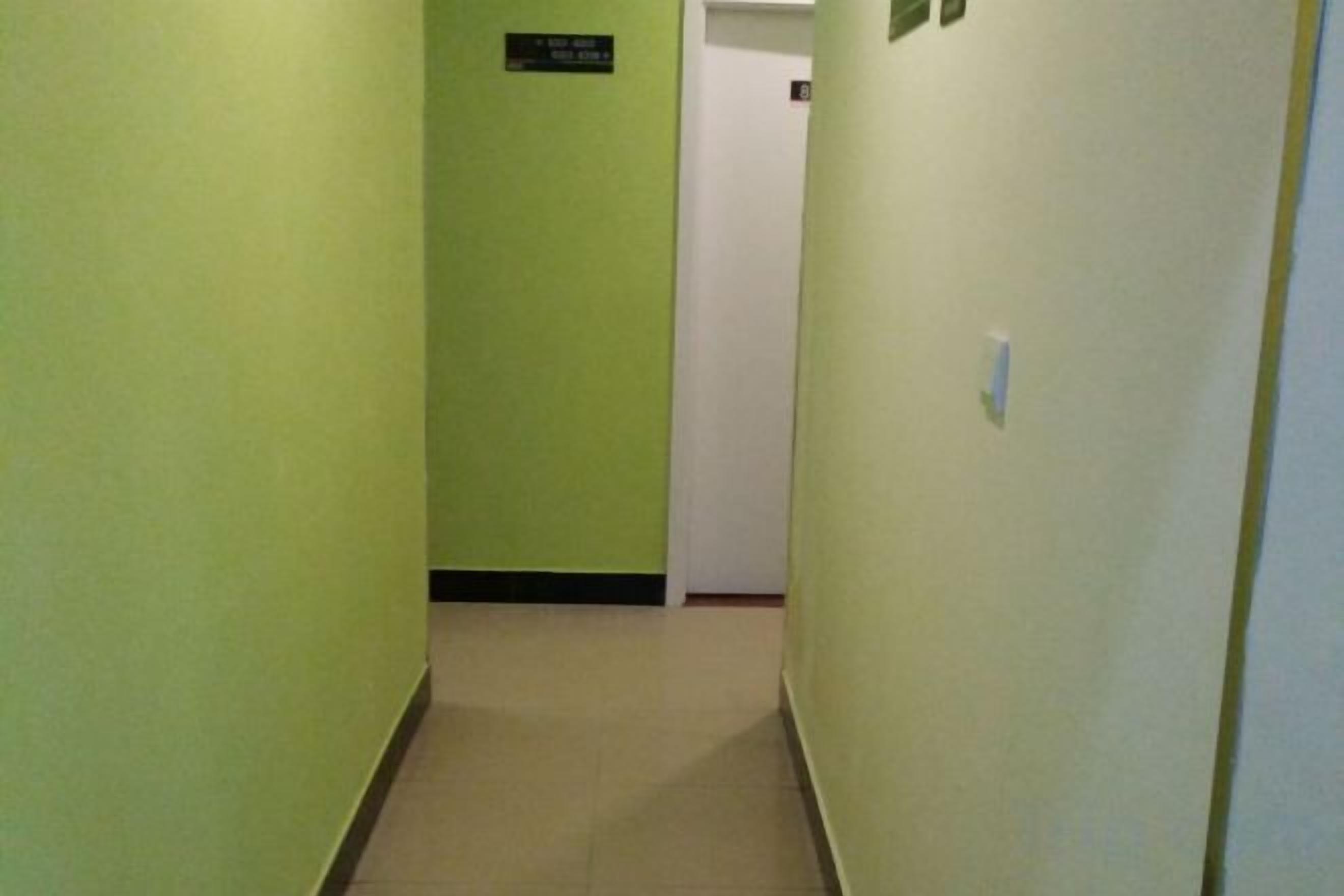 A narrow hallway with green walls and a white door at the end.