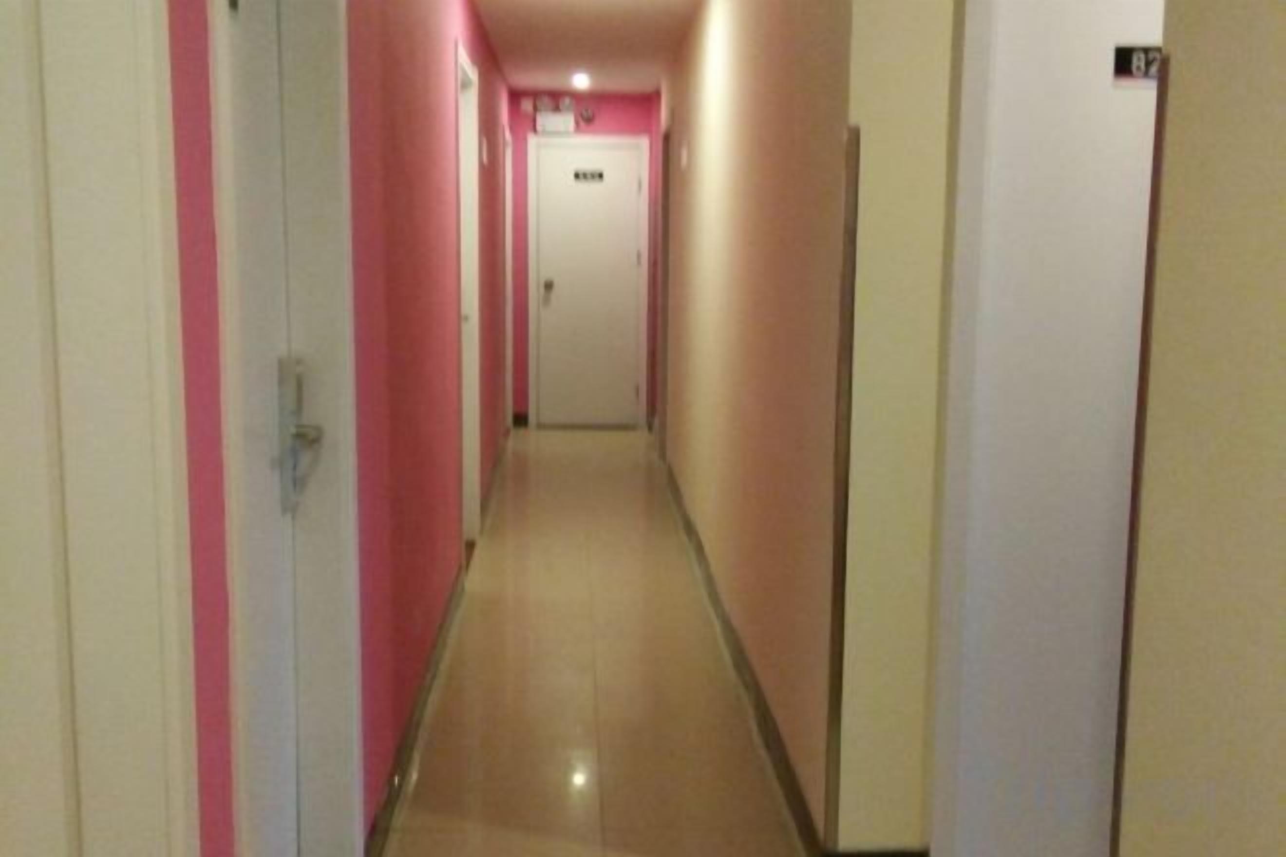 A narrow hallway with doors on both sides, leading to a room at the end.