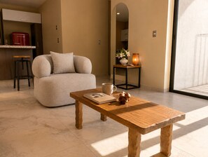 A modern living room with a sofa, a wooden coffee table, a small side table with a vase, and a kitchen area in the background. - PH King CityViews Suite / Daily Clean (guadalajara)