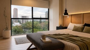 Une chambre à coucher moderne avec une grande fenêtre, un lit, une table de chevet et un luminaire suspendu.