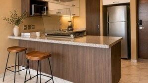 A modern kitchen with a central island, bar stools, a microwave, a stove, and a refrigerator.