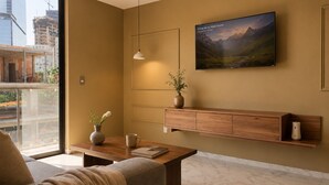 A modern living room with a sofa, coffee table, and a mounted TV displaying a mountain landscape.