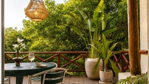 Une terrasse extérieure avec une table, des chaises, un luminaire suspendu et des plantes en pot.