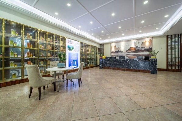 A hotel lobby with a reception desk, a seating area, and a display of various items. - Meizhou Tiandiren Garden Hotel (Meijiang Meixian People’s Square) (Meizhou)