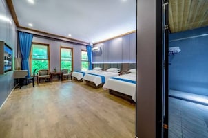 Habitación de hotel con dos camas, un escritorio, una silla y vista a zonas verdes.