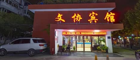 Fachada de hotel roja con señalización iluminada.