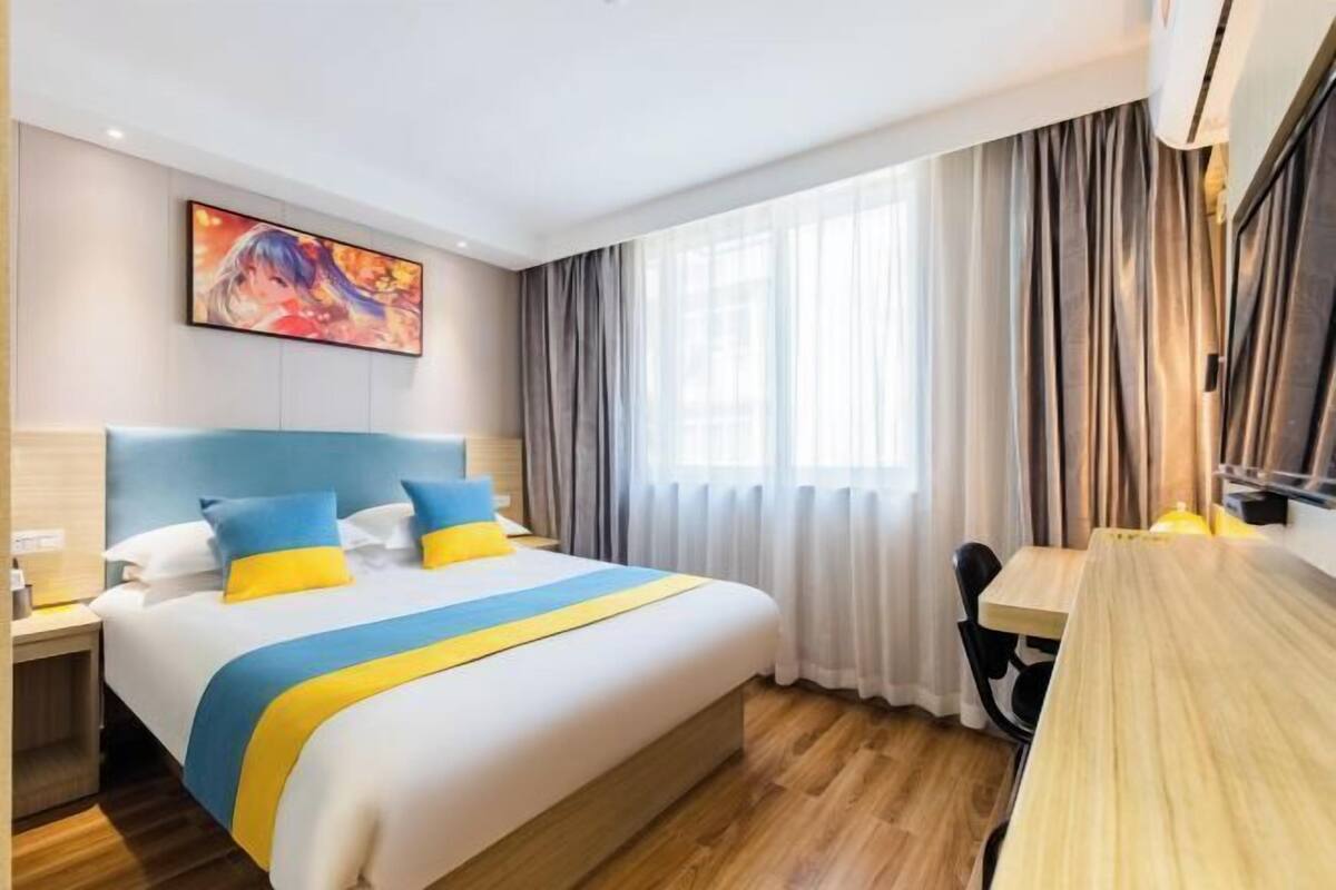 Habitació d'hotel amb un llit gran, un escriptori i un quadre a la paret.
