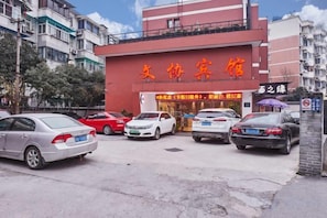 A hotel with a red facade and multiple cars parked in front. - Wenxie Hotel (Hangzhou)