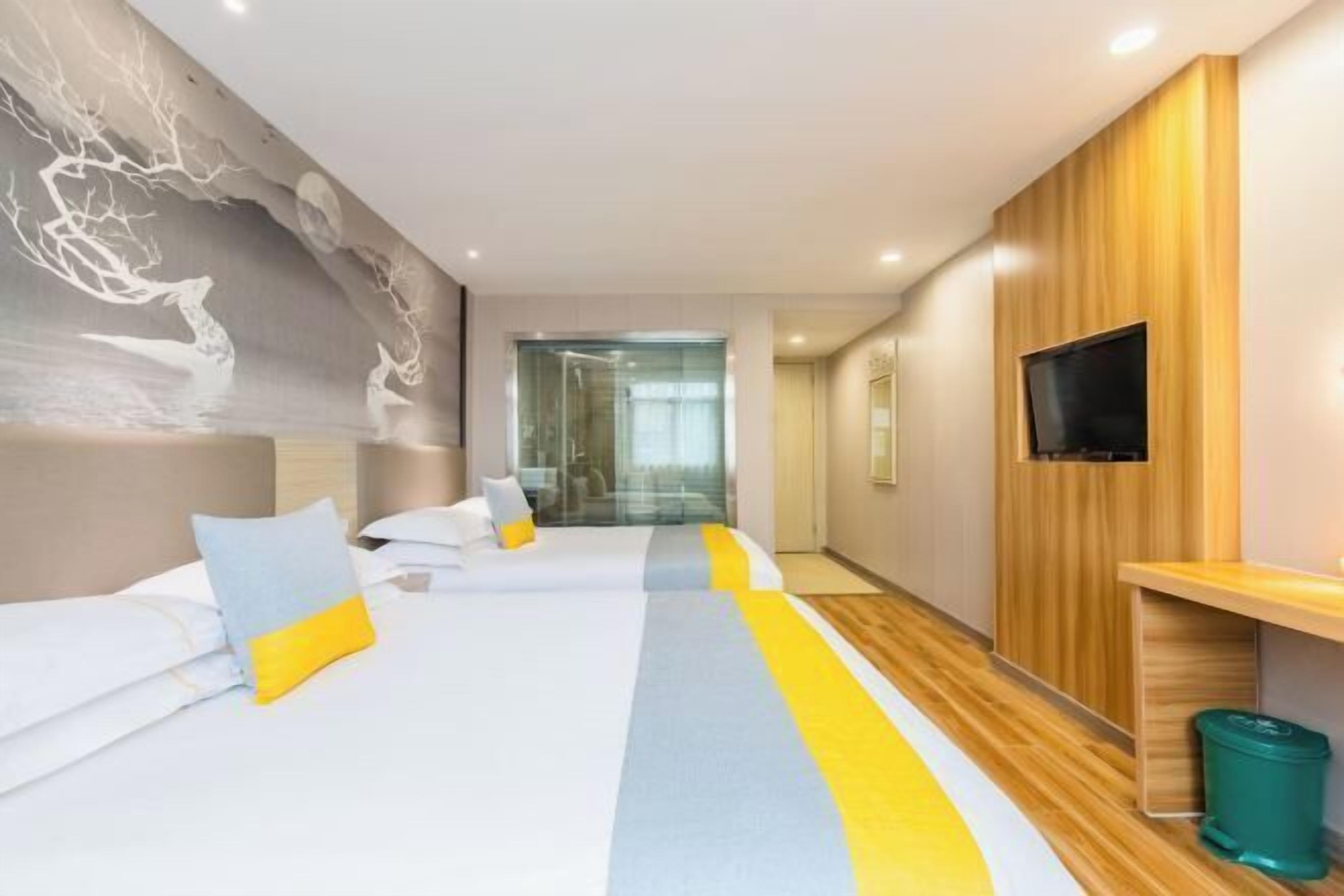 Une chambre d’hôtel moderne avec un grand lit, un téléviseur fixé au mur et un panneau décoratif en bois sur le côté.