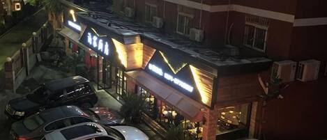 A hotel with a parking lot, multiple cars, and a well-lit entrance.
