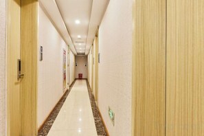 A hotel corridor with doors on both sides, a tiled floor, and a red emergency exit sign. - Wenxie Hotel (Hangzhou)