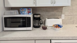 Et køkken med mikroovn, brødrister, kaffemaskine og cornflakes.