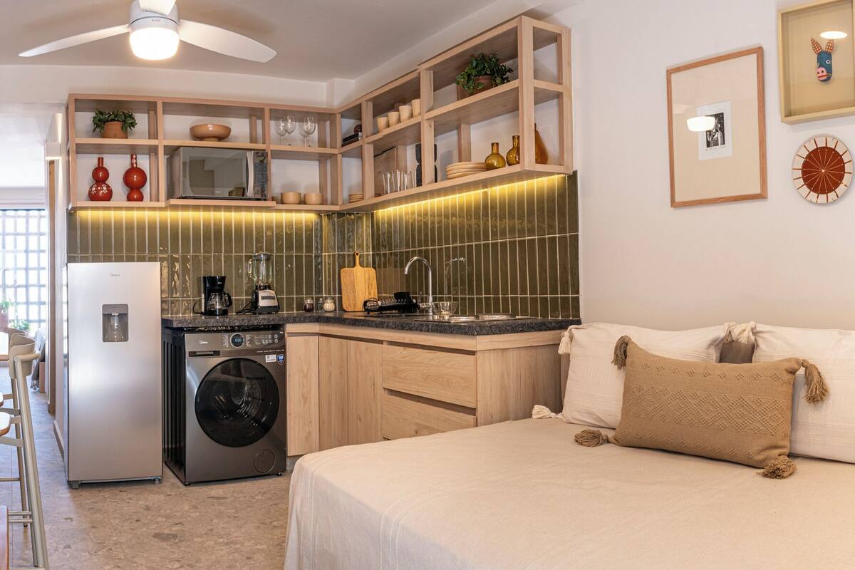Eine kleine Küche mit Waschmaschine, Kühlschrank und einer Arbeitsplatte mit Kaffeemaschine.