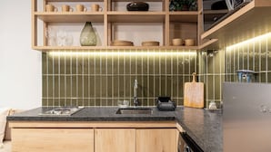 A kitchen with wooden cabinets, a granite countertop, a sink, and a stainless steel refrigerator. - Casa Teresa by Barrio México (Guadalajara)