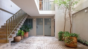 A clean, modern building entrance with a staircase, two doors, and potted plants. - Casa Teresa by Barrio México (Guadalajara)