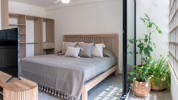 A bedroom with a bed, a wooden headboard, a bench, and a potted plant. - Casa Teresa by Barrio México (Guadalajara)