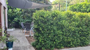 A patio area with a chair, a table, and a potted plant. - Mountain Views beside the Seaside. (Mount Coolum)