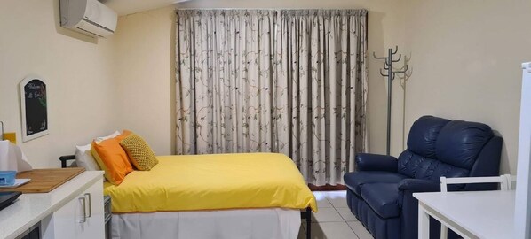 Un dormitorio con una cama, un escritorio, una silla y un sofá.
