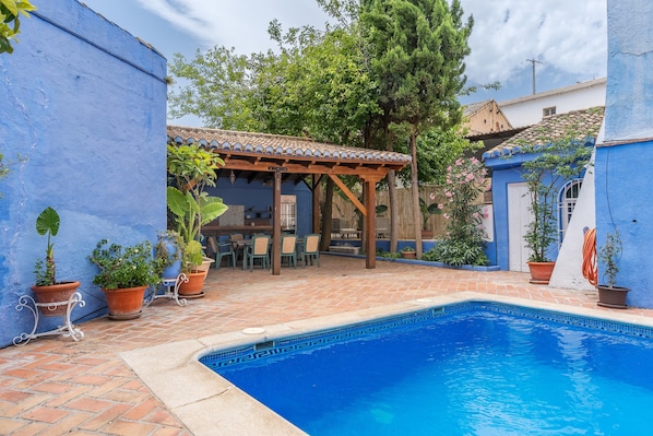 Un espace aménagé au bord de la piscine, avec une pergola, des plantes en pot et une terrasse carrelée.