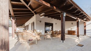 An outdoor covered patio area with wicker furniture, a wooden table, and a cabinet.