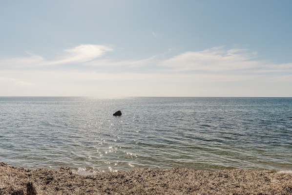 Ein ruhiges Meer mit einer felsigen Küste und blauem Himmel.