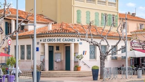 Un edificio con un cartel que dice 'LE CROIS DE CAGNES' y un restaurante llamado 'Le GRILL' al fondo.