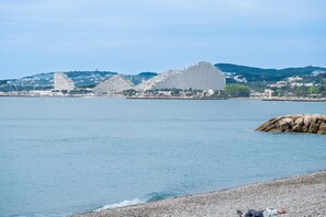 Une vue sur la côte, avec des bâtiments modernes, une plage de galets et une eau calme.