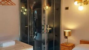 A room with a glass-enclosed shower, a wooden bedside table, a lamp, and a bed. - Room 'Primula' with Mountain View, Shared Pool and Wi-Fi (Santo Stefano d'Aveto)