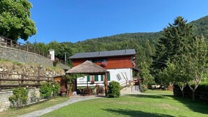 Una casa rústica con estructura de techo de paja, un muro de piedra y un césped bien cuidado.