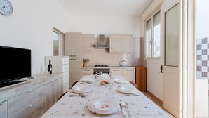 Une cuisine moderne avec une table à manger pour deux personnes, un téléviseur et une horloge au mur.