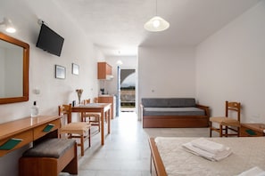 Une chambre à coucher comprenant un lit, un bureau, une chaise, un canapé, une télévision et une vue sur l’extérieur.
