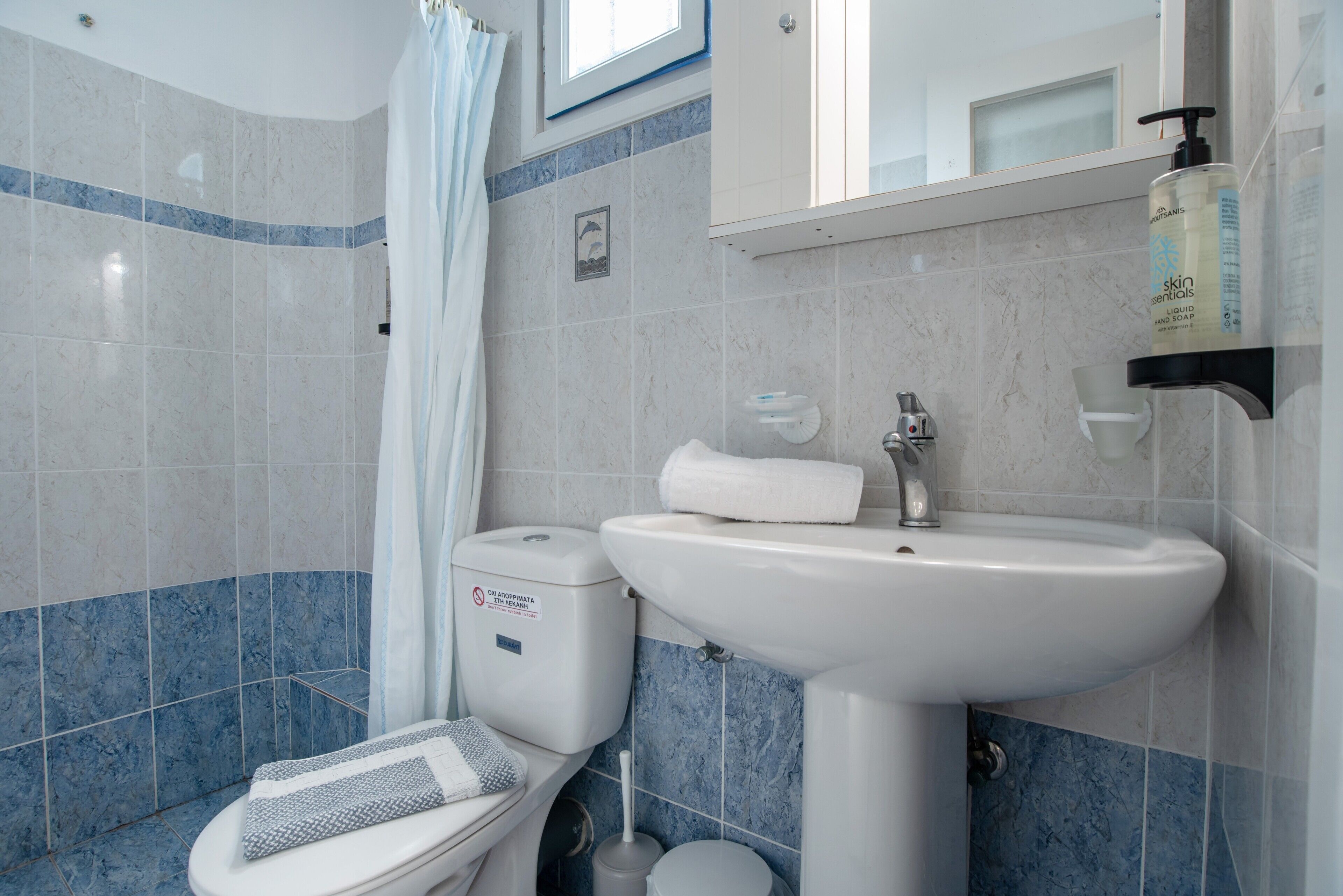 A bathroom with a toilet, sink, and shower curtain.