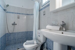 Une salle de bain équipée d’une douche, de toilettes, d’un lavabo et d’un porte-serviettes.