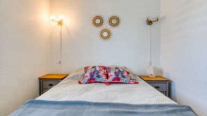 A bedroom with a bed, two bedside tables, a wall-mounted lamp, and decorative wall art. - Superb Apartment on Fishermen's Island with Sea View, Private Terrace & Air Conditioning (Agde)