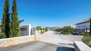 A residential street with houses, a paved road, and a stone wall.