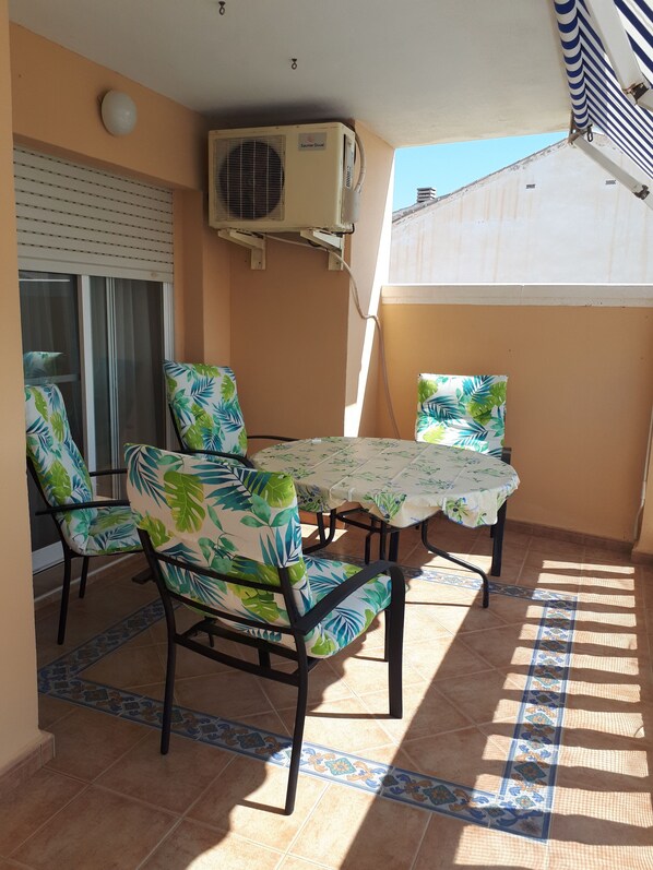 A patio area with a table and chairs, an air conditioning unit, and a view of the outside.
