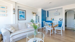 A living room with a sofa, a glass coffee table, and a dining area with chairs and a table.