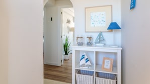 A hallway with a white console table, a framed map, a blue lamp, and wicker baskets.