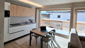 Una cocina moderna con comedor, una computadora portátil sobre la mesa y un balcón con vistas.