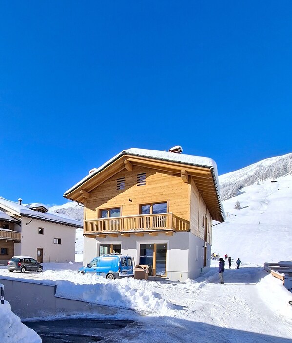 A wooden chalet with a balcony, surrounded by snow.