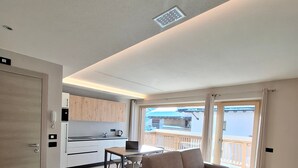 Un apartamento moderno con suelo de madera, un sofá, una mesa de comedor y una zona de cocina.