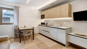 Una cocina moderna con comedor, armarios de madera, microondas integrado y televisor de pantalla plana.