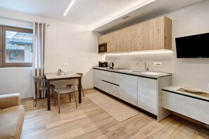 Une cuisine moderne avec un coin repas, des meubles en bois, un four à micro-ondes encastré et un téléviseur à écran plat.
