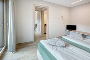 Una habitación de hotel moderna con una cama, un televisor y un baño visible a través de una puerta abierta.