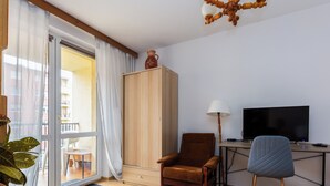 A living room with a wooden cabinet, a brown armchair, a blue chair, a TV, and a plant.