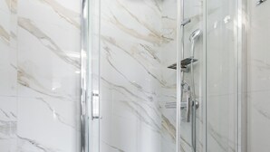 A modern shower with glass doors, a handheld showerhead, and a wall-mounted faucet. - Park Grabiszyński Standard Studio (Wrocław)