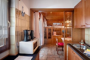 A compact kitchen with wooden cabinets, a microwave, a coffee maker, and a sink.