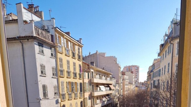 Un balcon avec une table dressée pour le petit-déjeuner, offrant une vue sur le paysage urbain.