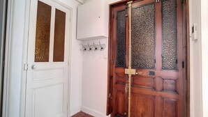 Un couloir avec une porte blanche et une porte en bois dotée de panneaux de verre.