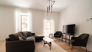 Uma sala de estar moderna com sofá, poltronas, mesa de centro e televisão.